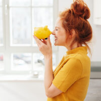 Eine rothaarige Frau freut sich über ein Sparschwein.