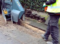 Ein Arbeiter geht hinter einer Bodenfräse her.