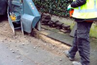 Neues Glasfaser-Ausbaugebiet in Hilden-Nord Ein Arbeiter geht hinter einer Bodenfräse her.